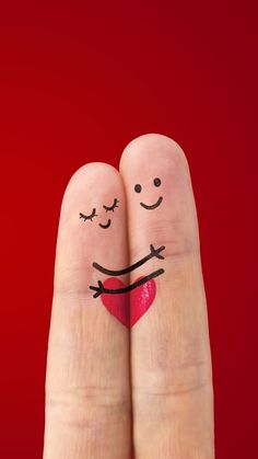 two fingers with faces drawn on them and one has a red heart in the middle