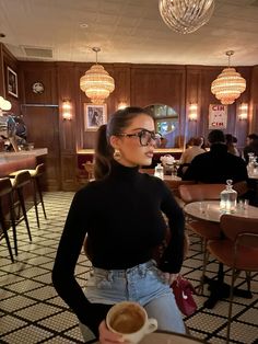 a woman standing in a restaurant holding a cup of coffee