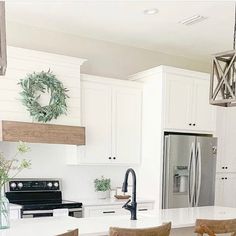 a kitchen with white cabinets and an island in front of a stove top oven surrounded by chairs