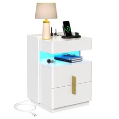 a white night stand with a phone and other items on it, including a lamp