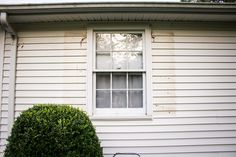 a bicycle parked in front of a white house with a window on the side of it