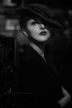 black and white photograph of a woman wearing a hat with veil on it's head