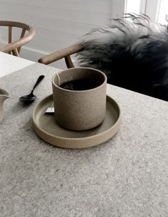 a cup and saucer sitting on top of a table next to a plate with spoons