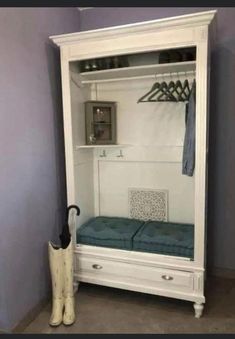 a white cabinet with a blue cushion and umbrella in it next to a pair of boots