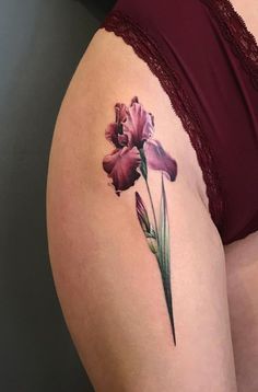 a woman's thigh with a pink flower tattoo on her left side ribcage