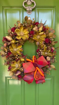 a green door with a red and orange wreath hanging on it's front door