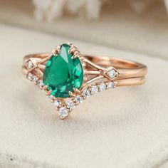 a ring with an oval cut green stone surrounded by small white diamonds on a cushioned surface