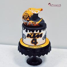 a three tiered cake decorated with an orange and black motorcycle on it's side