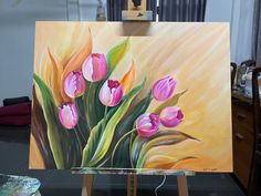 an easel with a painting of pink tulips on it