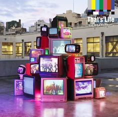 there are many tvs stacked on top of each other in front of a building