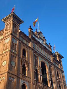 an ornate building with flags on top and blue sky in the backgroung