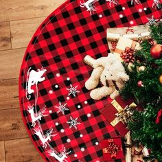 a red and black plaid christmas plate with a teddy bear next to it on a wooden floor