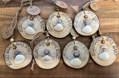 six seashells are hanging from the side of a wooden tray on a table