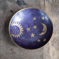 a purple and gold plate with stars and the moon on it sitting on a table