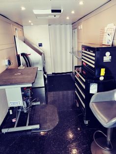 the inside of a small storage room with many drawers and stools on each side