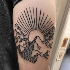 a man's arm with a mountain and sun tattoo design on the upper half of his arm