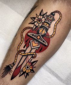 a tattoo on the leg of a man with an arrow and dagger in it's center