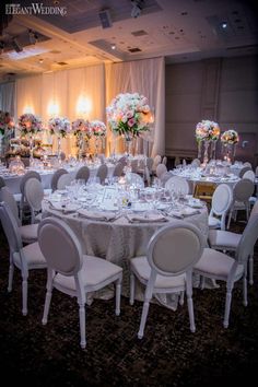 the tables are set with white linens and centerpieces for an elegant wedding