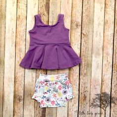 Floral peplum and bummies outfit- solid purple lavender sleeveless top and flowered shorties diaper Fitted Short Sleeve Bubble Romper For Spring, Cotton Tops Matching Set For Playtime, Fitted Purple Sets For Spring, Fitted Purple Spring Sets, Spring Purple Fitted Sets, Fitted Cotton Bloomers With Ruffles, Stretch Cotton Ruffle Sets, Fitted Peplum Sets For Spring, Stretch Cotton Sets With Ruffles