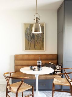 a kitchen table with chairs and a bench in front of the counter top, next to a painting on the wall