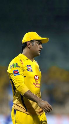 a man in a yellow uniform is standing on the field with his hands behind his back