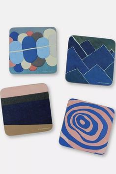 four square coasters with different designs on them, one in blue and the other in pink