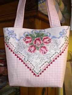 a pink and white tote bag with flowers on it hanging from a hook in a closet