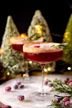 two glasses filled with red liquid and garnished with rosemary