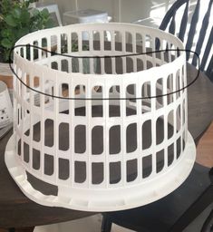 a white plastic basket sitting on top of a wooden table next to a black chair