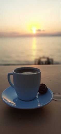 a cup of coffee sitting on top of a white saucer next to the ocean