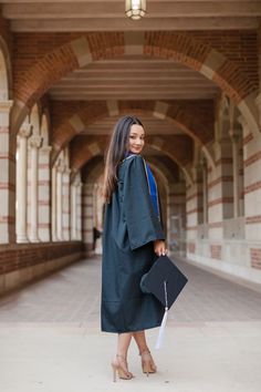 a woman in a graduation gown is walking down the street with her diploma and bag