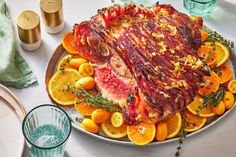 a large piece of meat sitting on top of an orange covered plate next to glasses and napkins