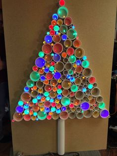 a christmas tree made out of empty cups is shown in front of a cardboard board