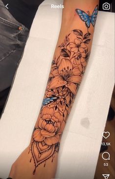 an arm tattoo with flowers and butterflies on it