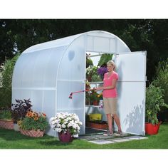 a woman in pink shirt standing next to a white greenhouse