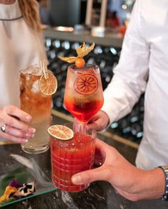 two people holding up drinks at a bar