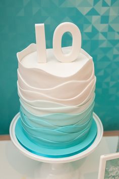 a white and blue cake sitting on top of a table next to a sign that says 10