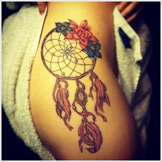 a woman's arm with a tattoo on it that has flowers and a dream catcher