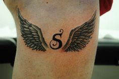 an image of a tattoo with wings on the back of someone's leg and letter s