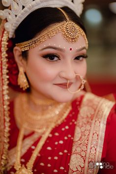 a woman wearing a red and gold bridal outfit with an elaborate head piece on her head