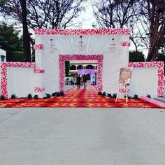 the entrance to a wedding ceremony is decorated with pink and white flowers on red carpet