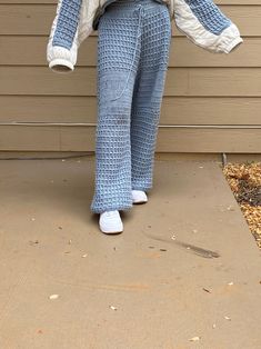 a woman in blue and white pants standing on a porch with her hands behind her back