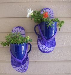 two blue vases with flowers in them hanging on the side of a house wall