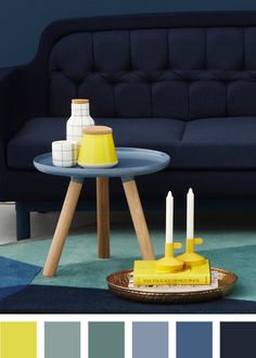 a living room with blue couch and yellow candles on the table in front of it