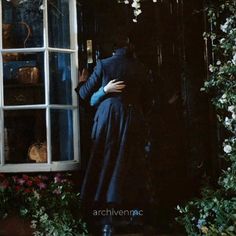 a woman standing in front of a window with her back to the camera and arms around her body