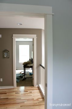 an open door leading to a living room with hard wood flooring and white walls