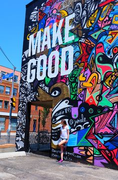 a woman standing in front of a colorful wall with the words make good written on it