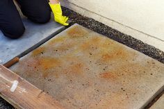 a person in yellow rubber boots is working on a concrete slab with a hammer and cement pad