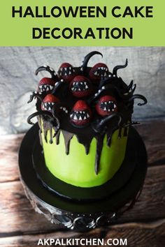 a green cake with black icing and red berries on top sitting on a wooden table