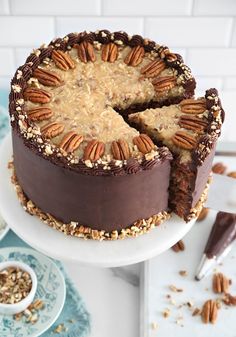 a chocolate cake with pecans on top and one slice cut out from the cake